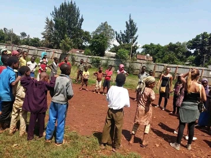 Children playing a game outdoors with volunteers