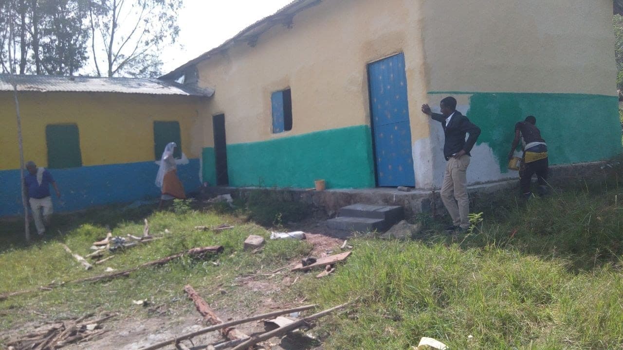 Volunteers painting the outside wall of a classroom