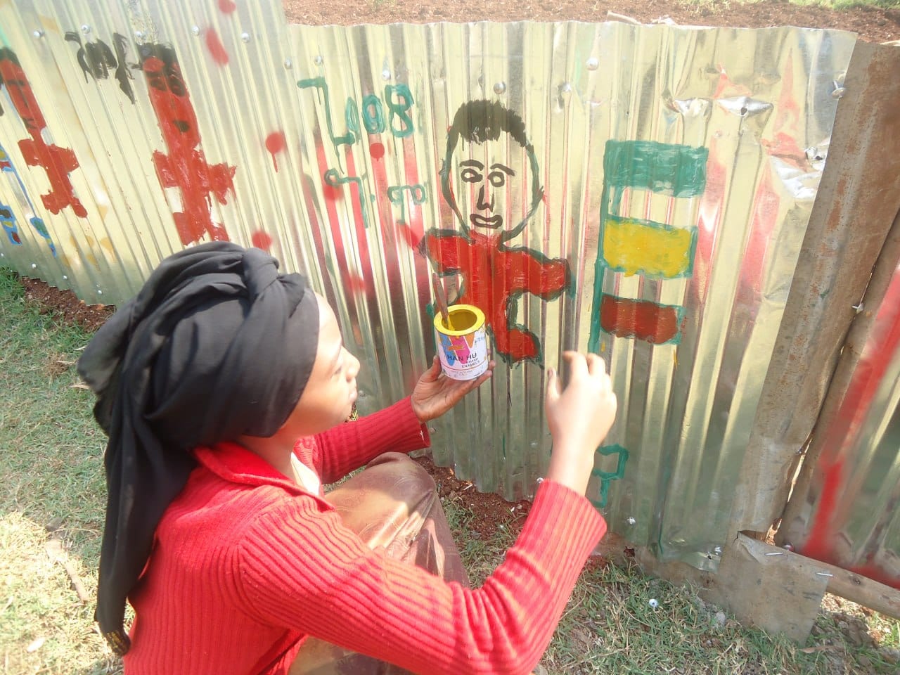 A girl painting a figure on the fence