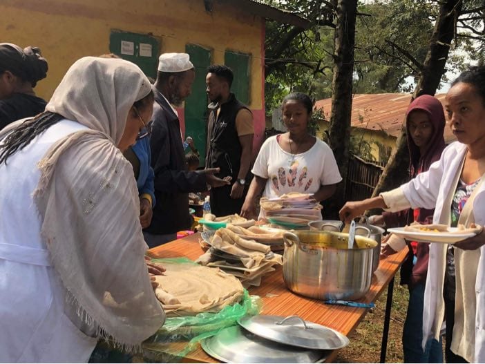 Volunteers serving injera and stew